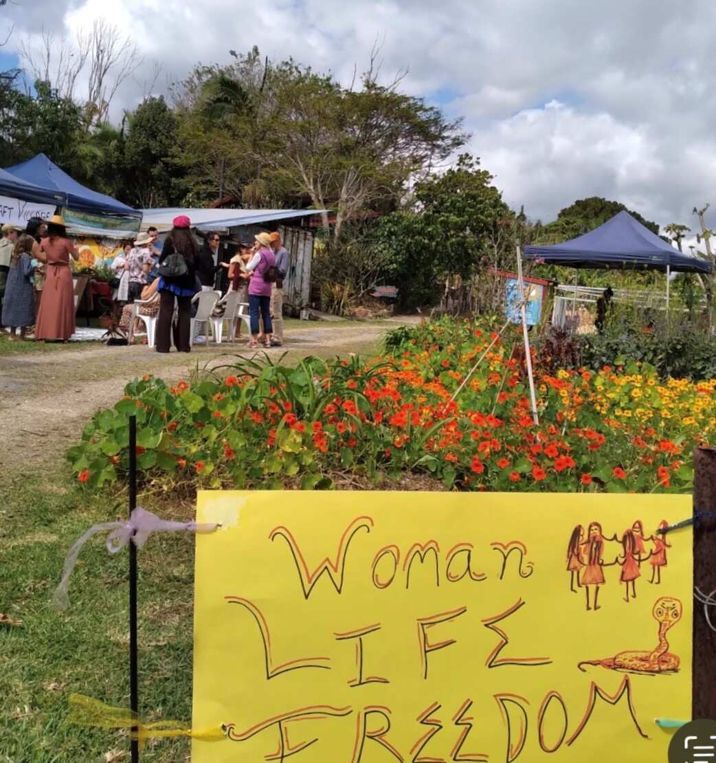 A yellow sign with writing Woman. Life. Freedom displayed at Kian Garden in Byron Bay 