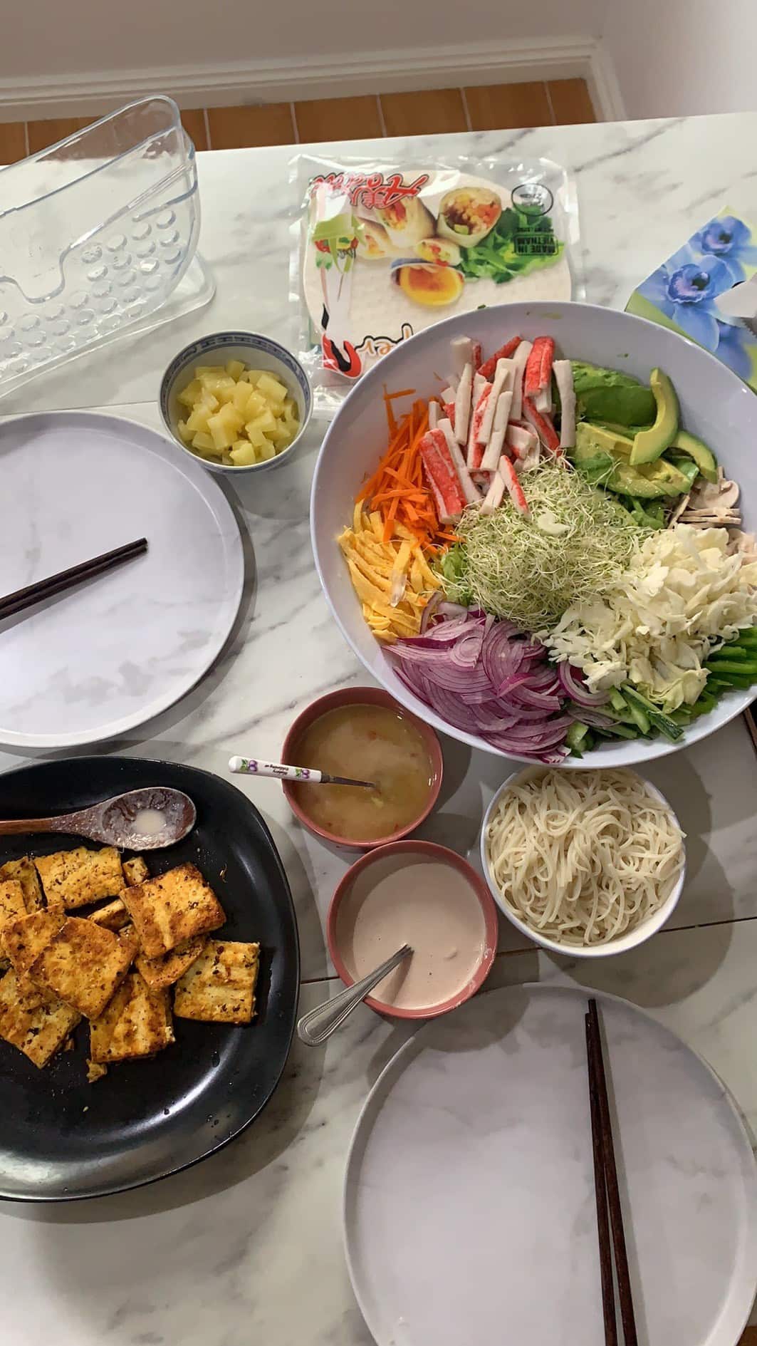 Salad in a bowl and tofu in a bowl on a marble table