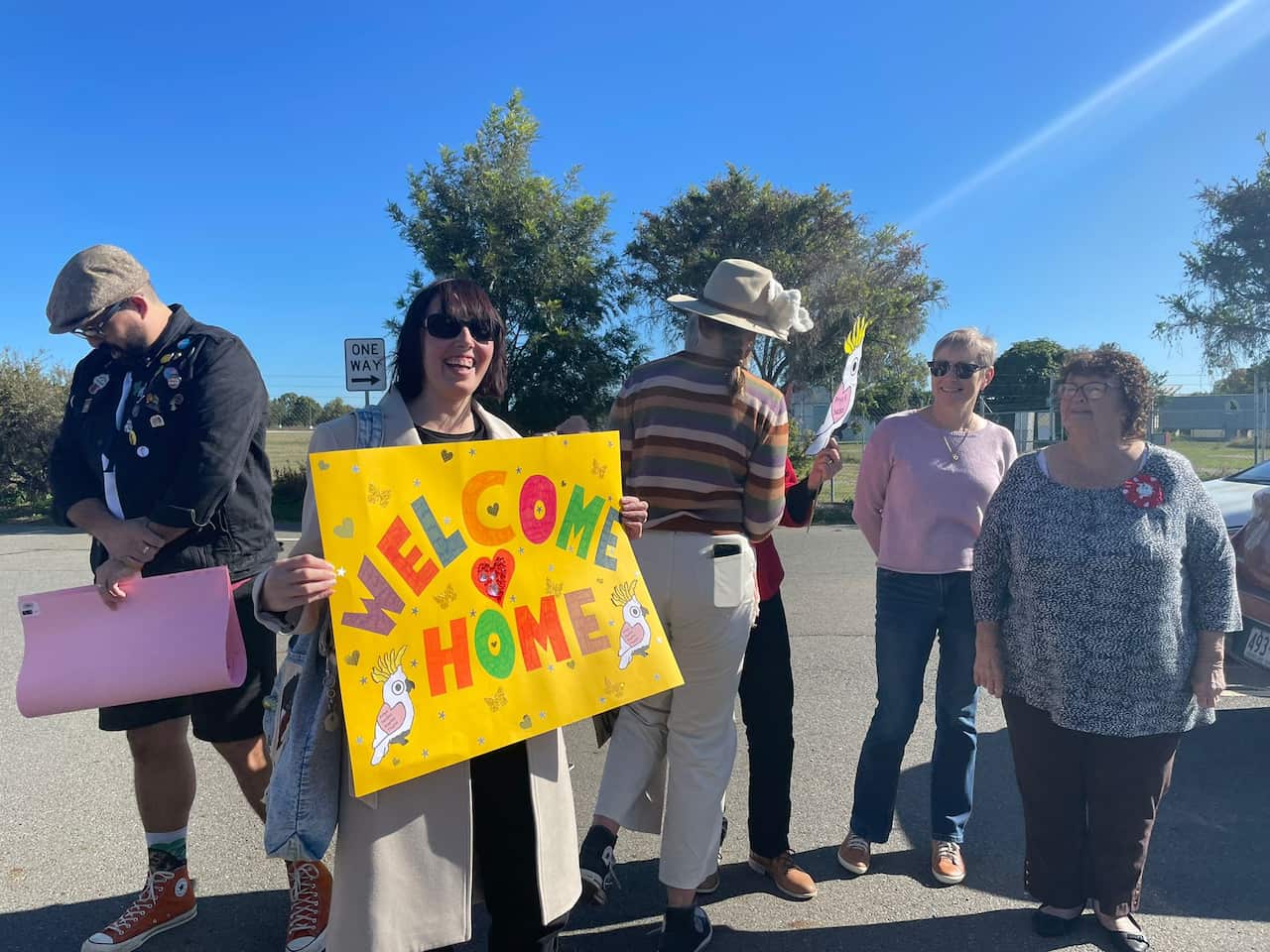 Woman holding yellow sign reading 'welcome home'