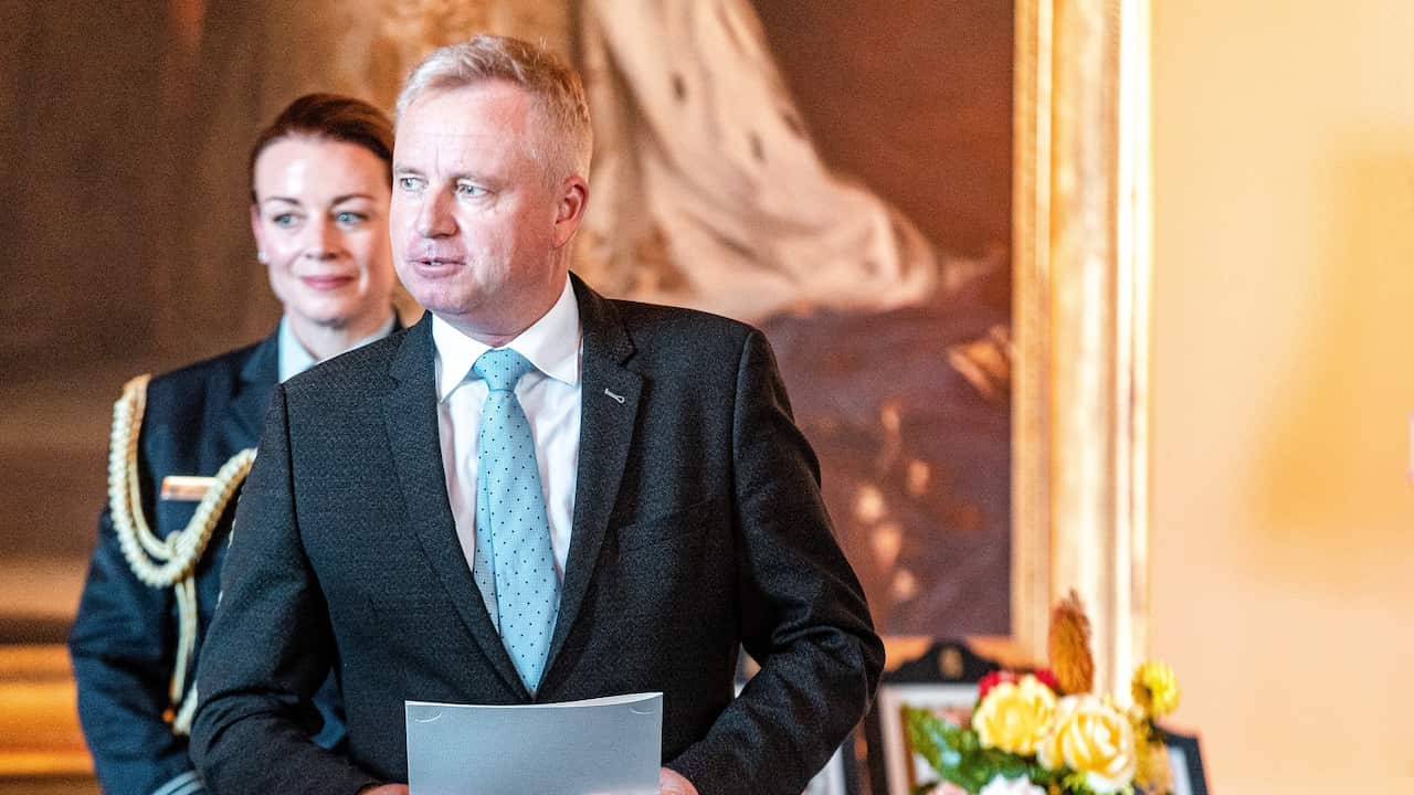 Man dressed in suit holding papers in official building.