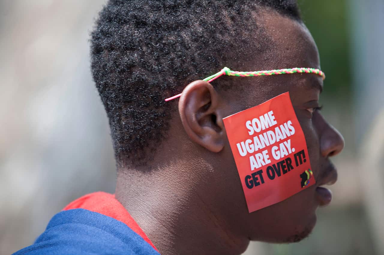 A man wearing a sticker that says 'some Ugandans are gay. Get Over it!'