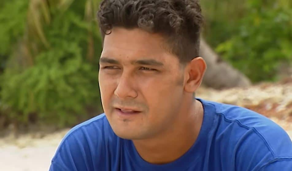A young man sitting on a beach.