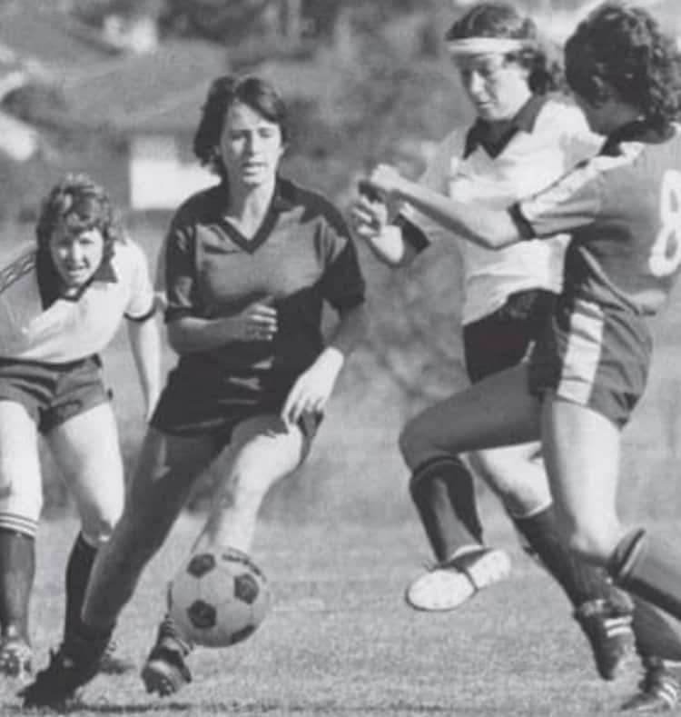 A black and white photo of women playing football