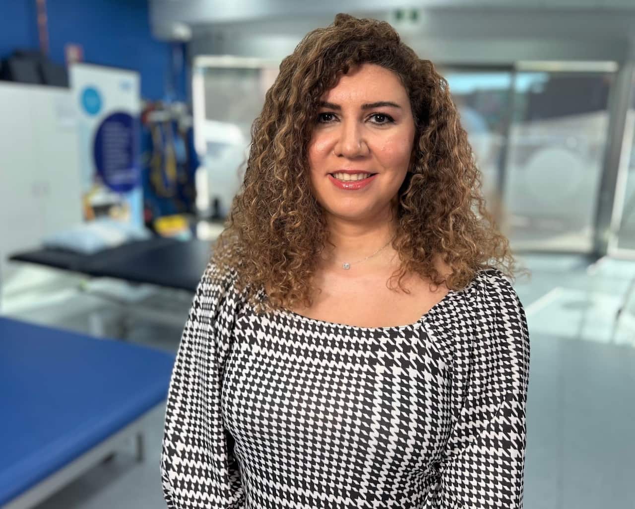 A woman in a black and white top standing in a gymnasium.