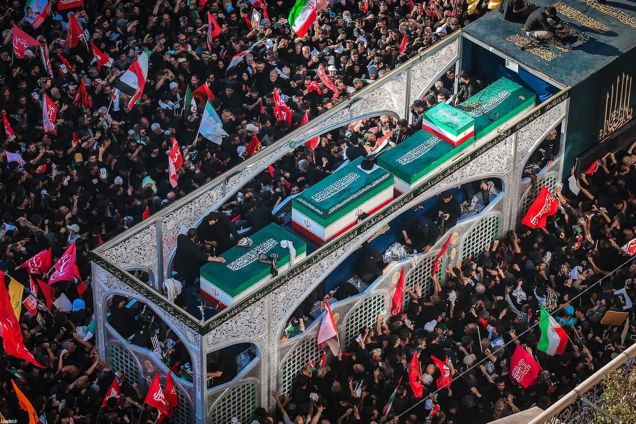 Crowds surround a coffin.