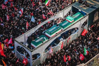 Crowds surround a coffin.