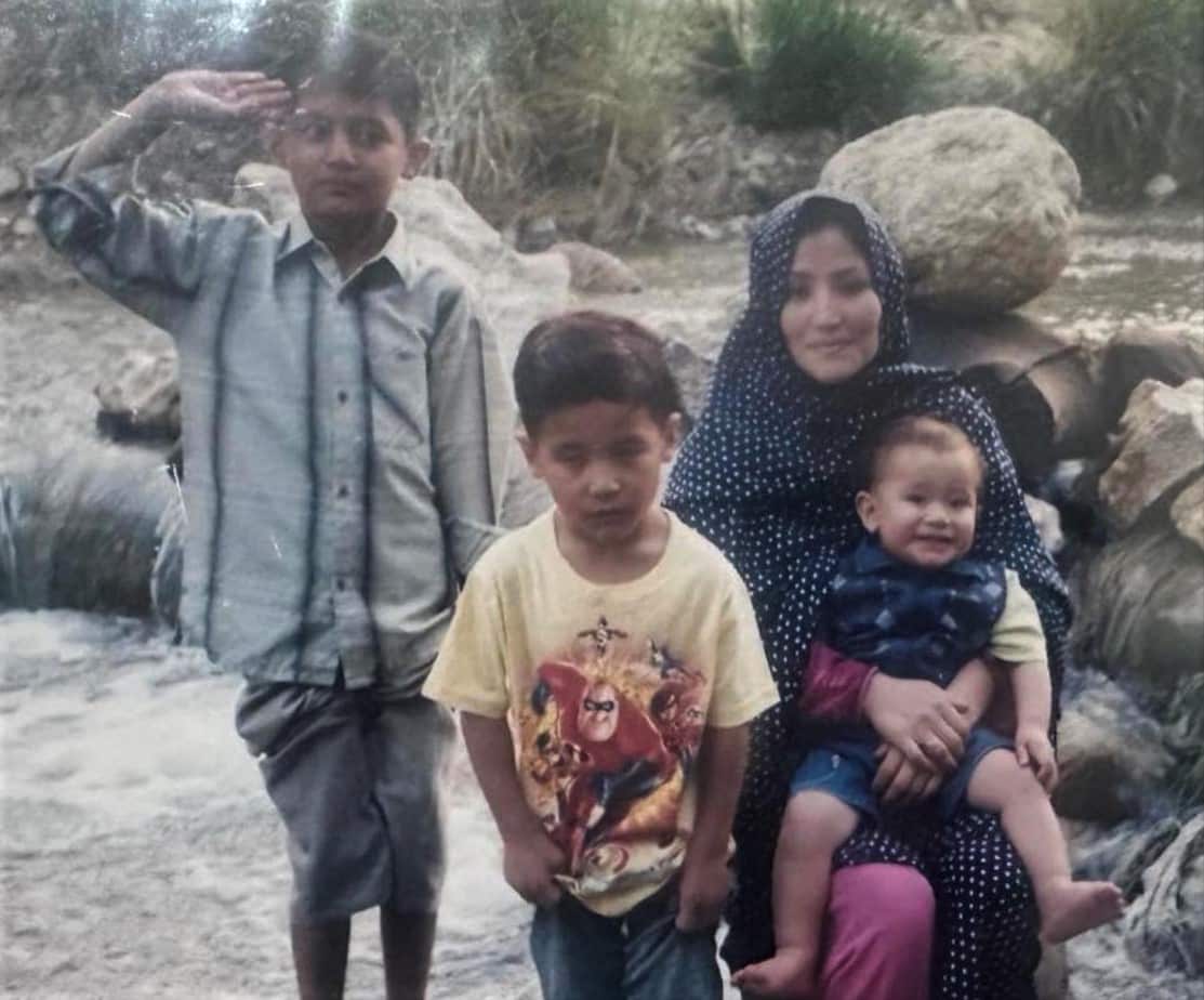Two boys, a woman and a baby pose for a photograph in a creek bed.