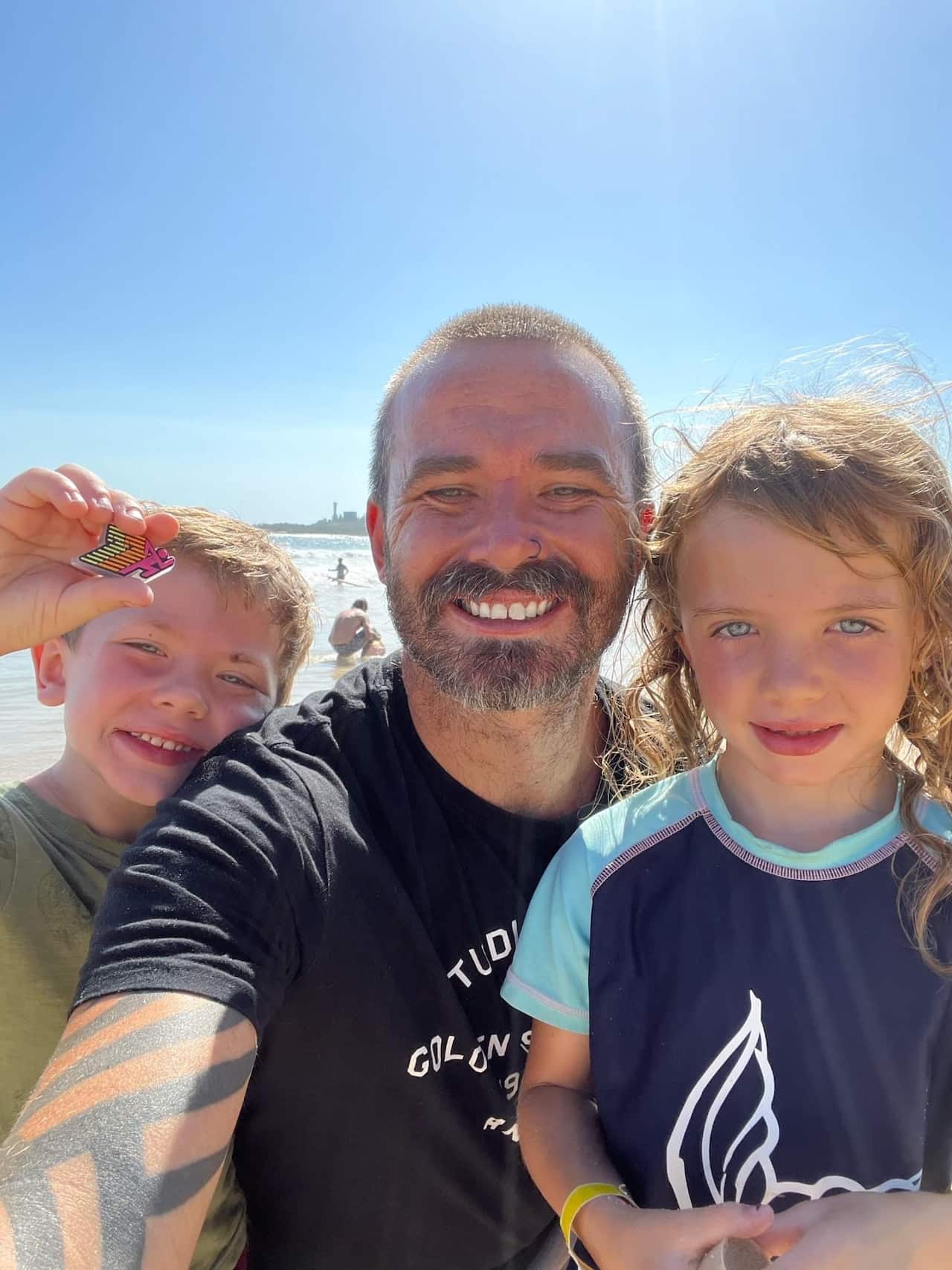 A dad with his two young children at the beach. 