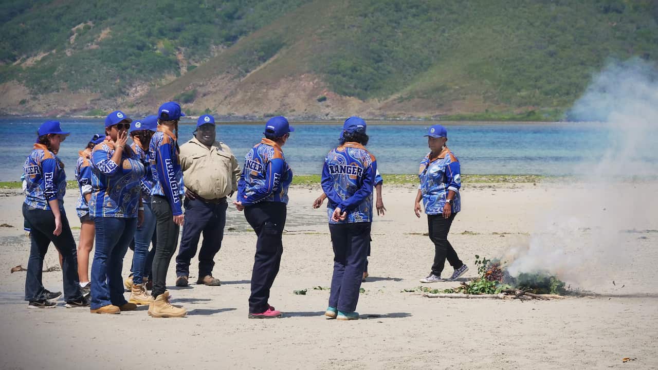 Indigenous women rangers doing ceremony on beach.