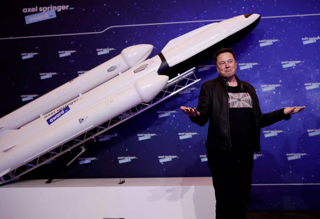 Elon Musk standing next to a model of a rocket 