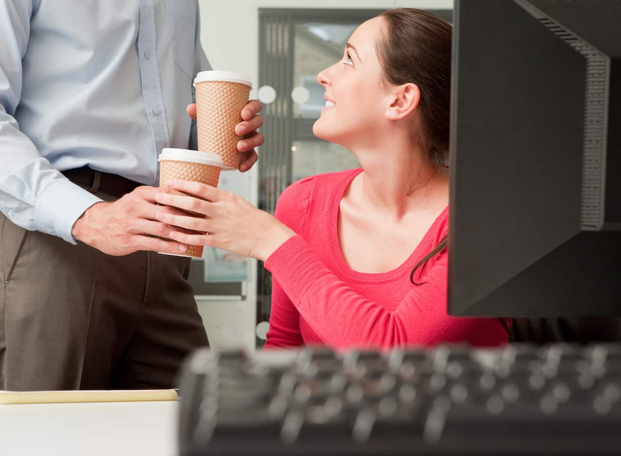 A male colleague brings a female colleague a coffee