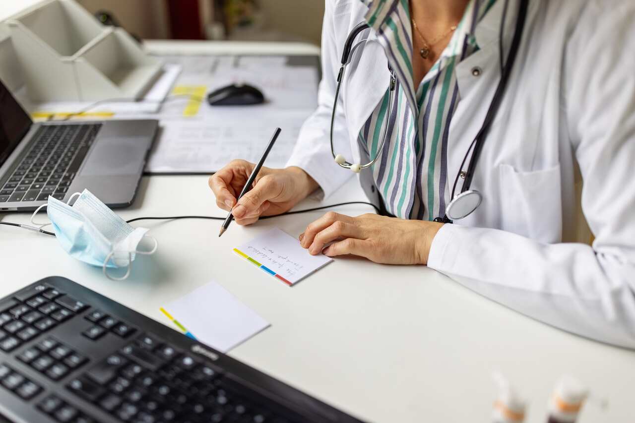 Doctor making notes while on video call with patient