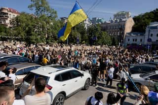 Protesters wave signs and Ukrainian flags in a town square.