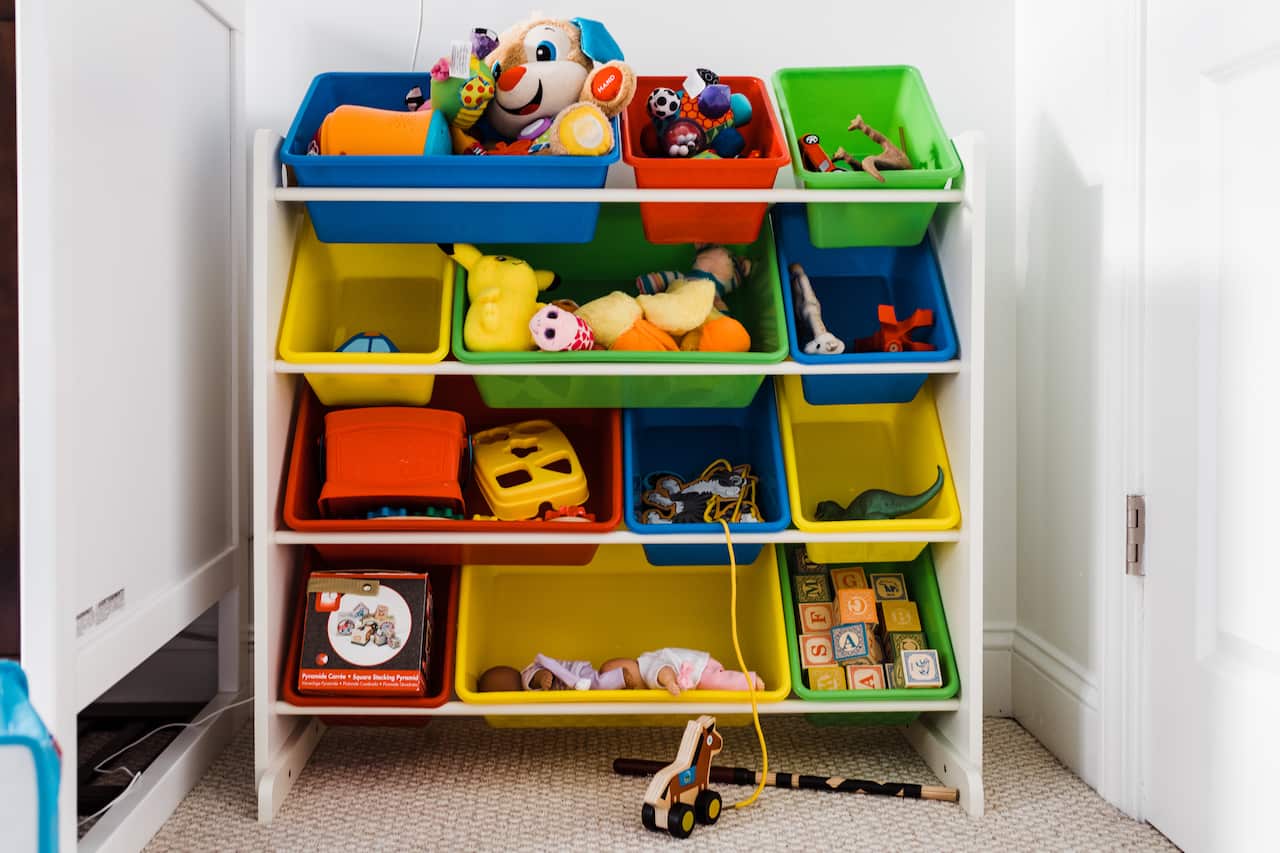 Children's toys sit in large tubs on a shelf.