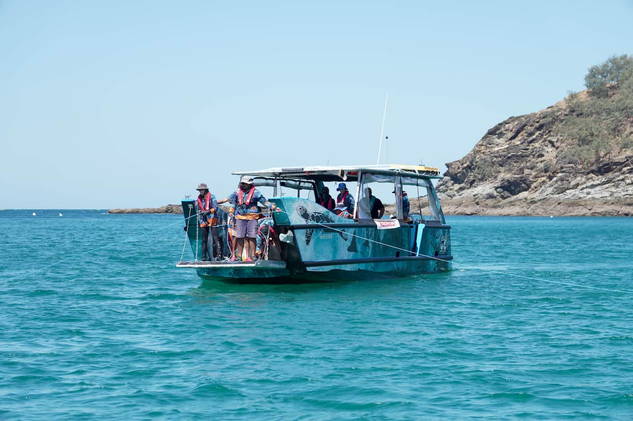 people on boat on ocean putting rope into water