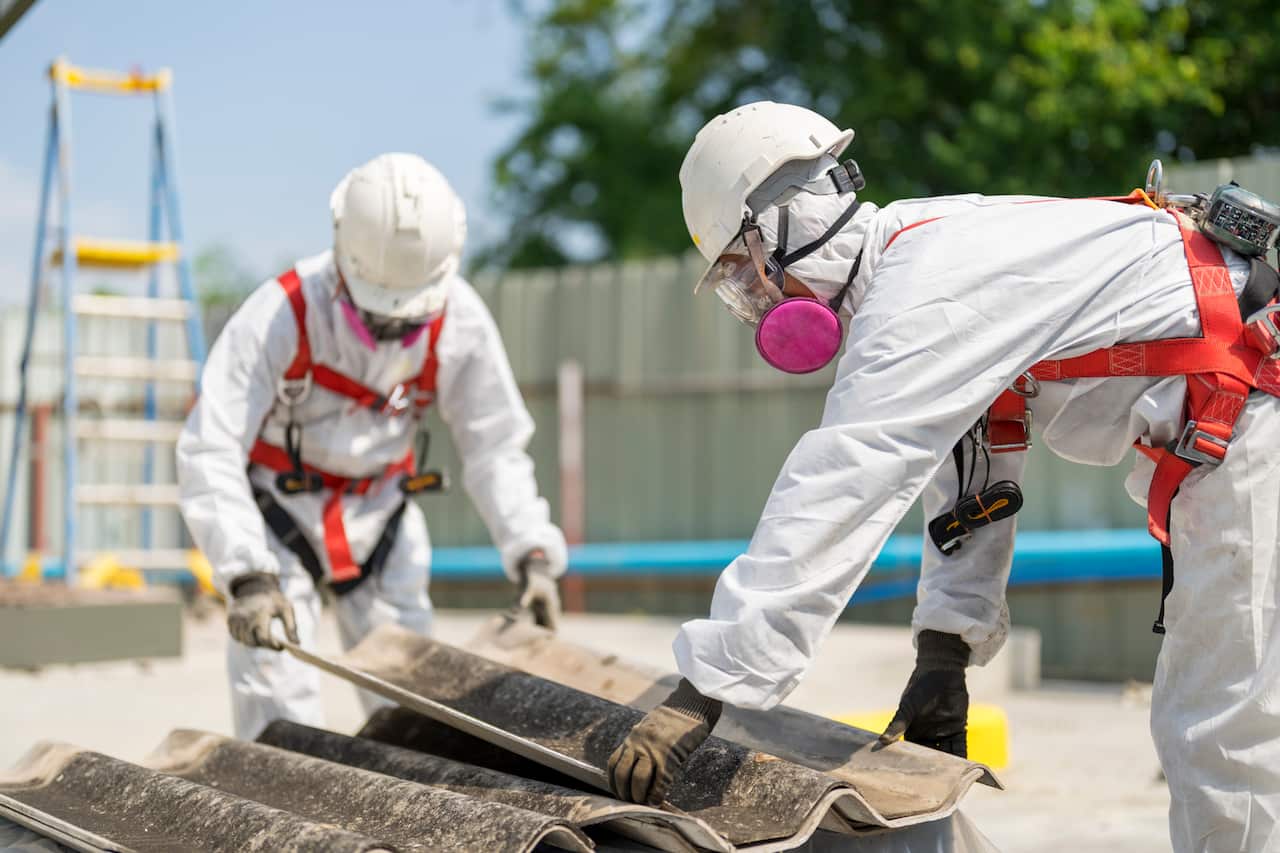 Safety is our top priority. Workers wearing full body protective clothing while working with the asbestos roof tiles.