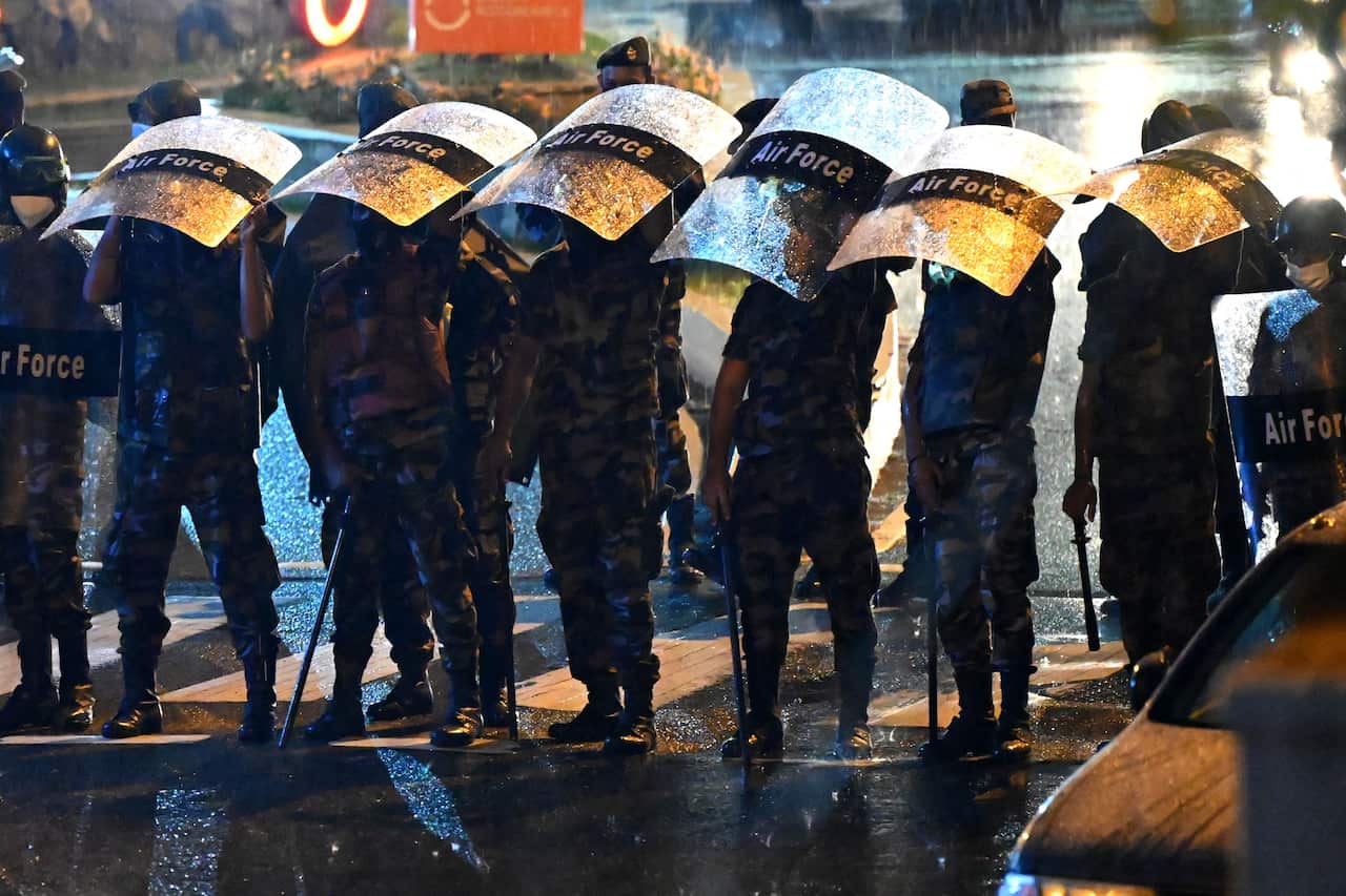 Anti-riot police officers are seen standing and holding their shields over their heads.