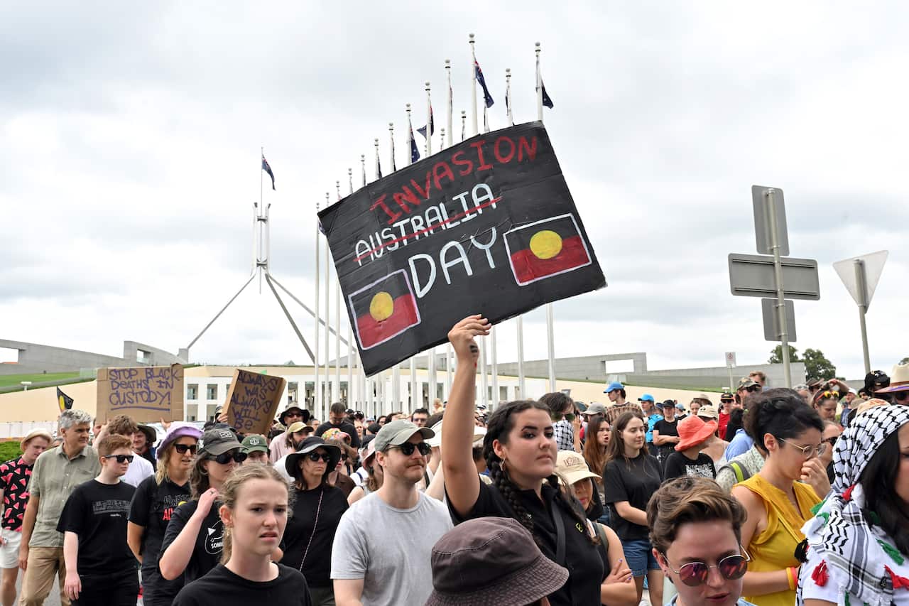 A large crowd of people marching outside Parliament House.