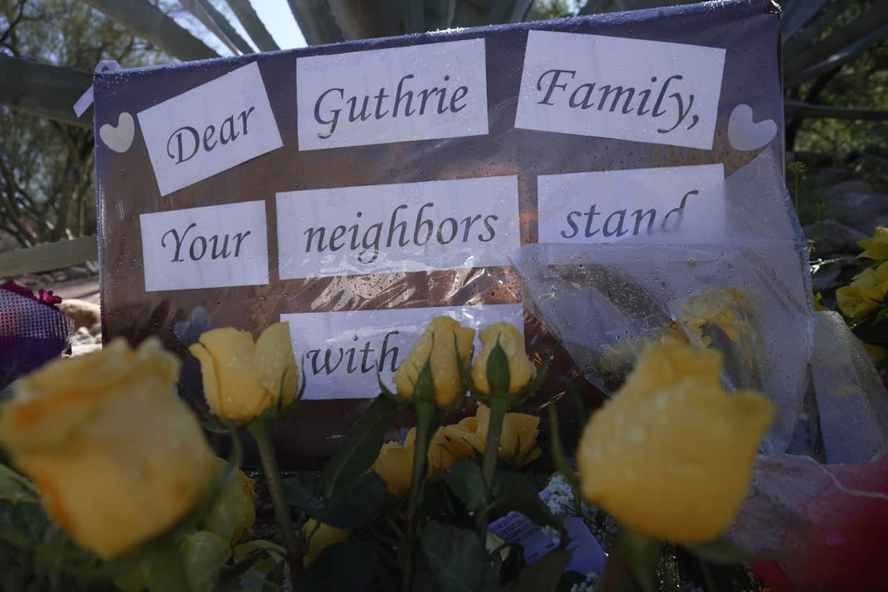 Yellow flowers and signs remain at a vigil outside of Nancy Guthrie’s home 
