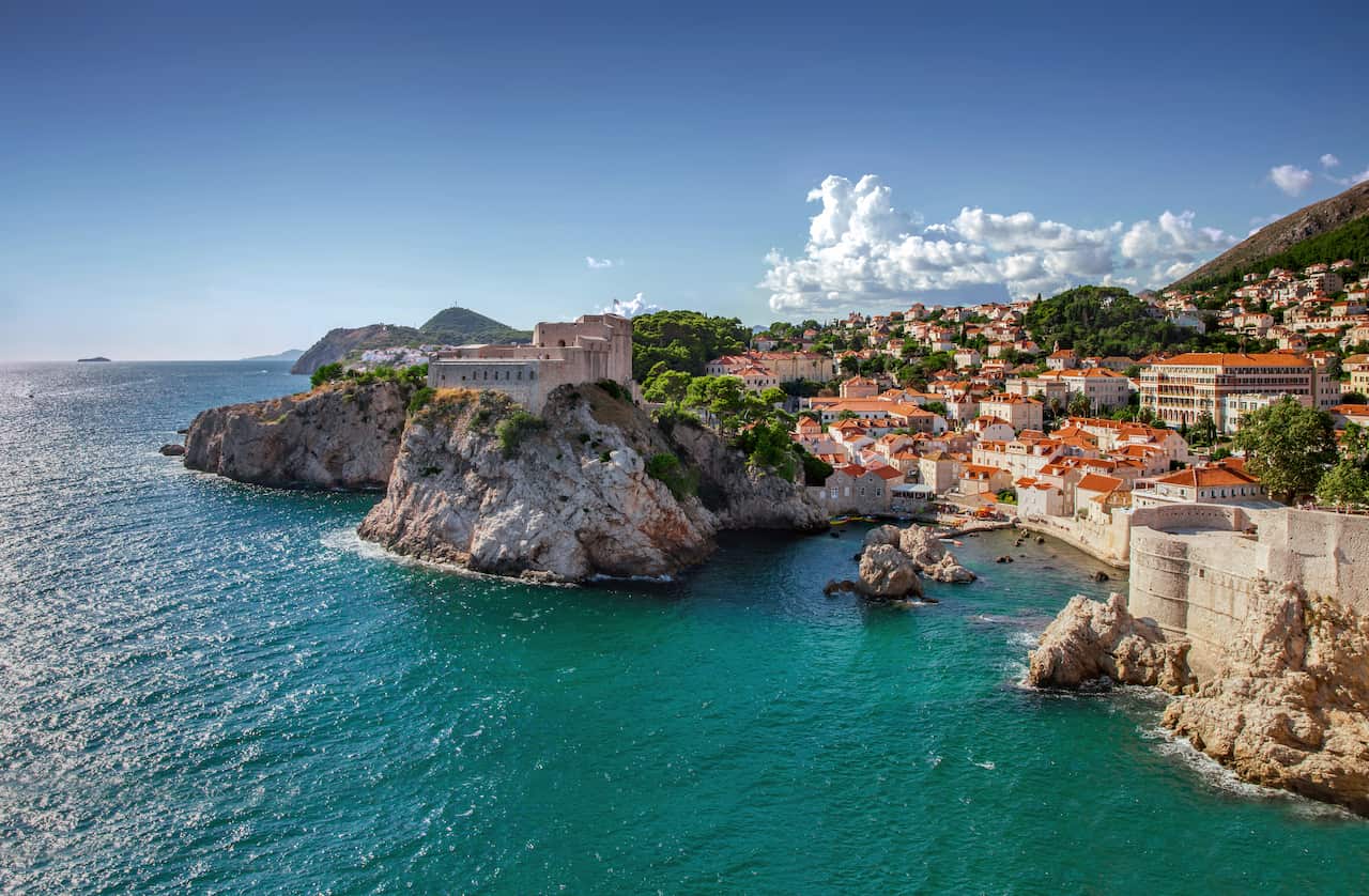 Aerial view of an old coastal town featuring buildings with red tile roofs.