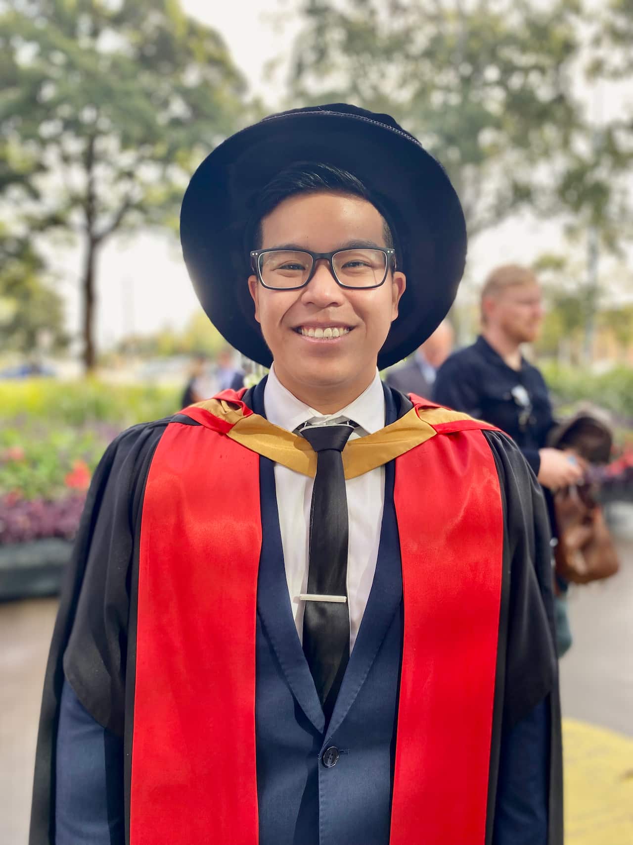 Dr Sandersan Onie wearing graduation gowns and smiling.
