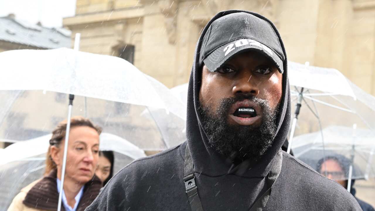 Kanye West wearing black hoodie and Balenciaga mouthguard