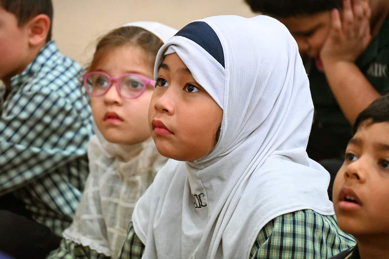 Seven year old Bonnisha and five year old Mahnoor sit quietly during school assembly at the Australian International Islamic College Darwin Campus