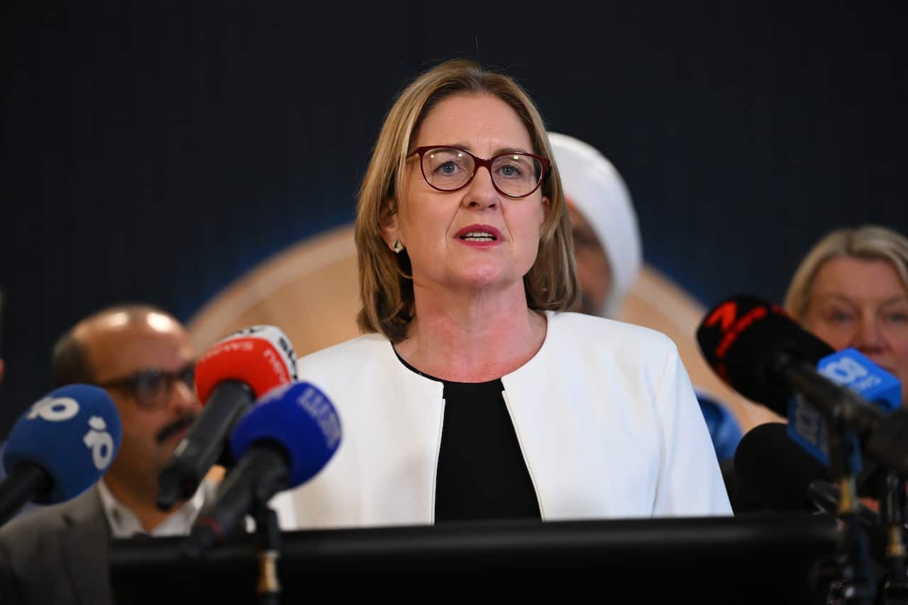 Premier Jacinta Allan speaks from podium to an array of media microphones