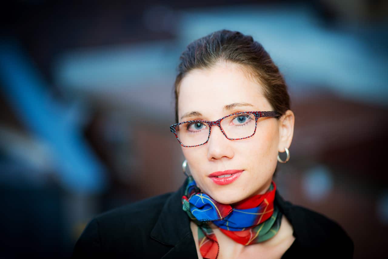 A woman with brown hair wearing glasses.