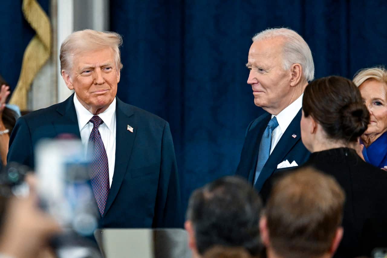 Donald Trump smiles as he stands next to Joe Biden.
