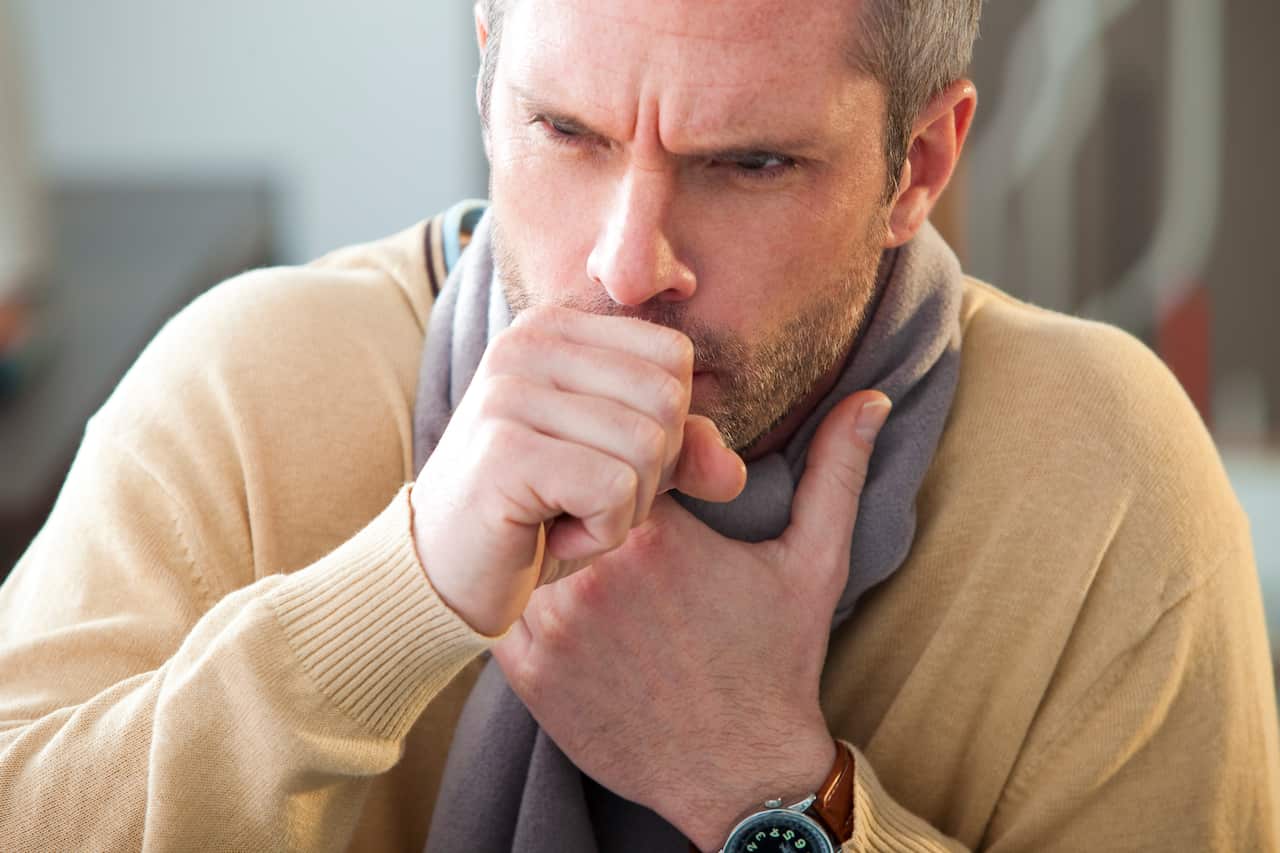 Man coughing, with a hand to his throat.