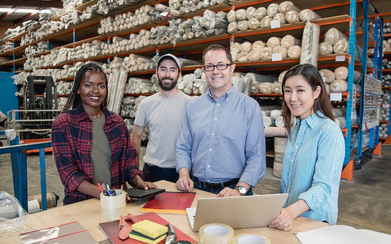 Portrait of four factory staff smiling towards camera