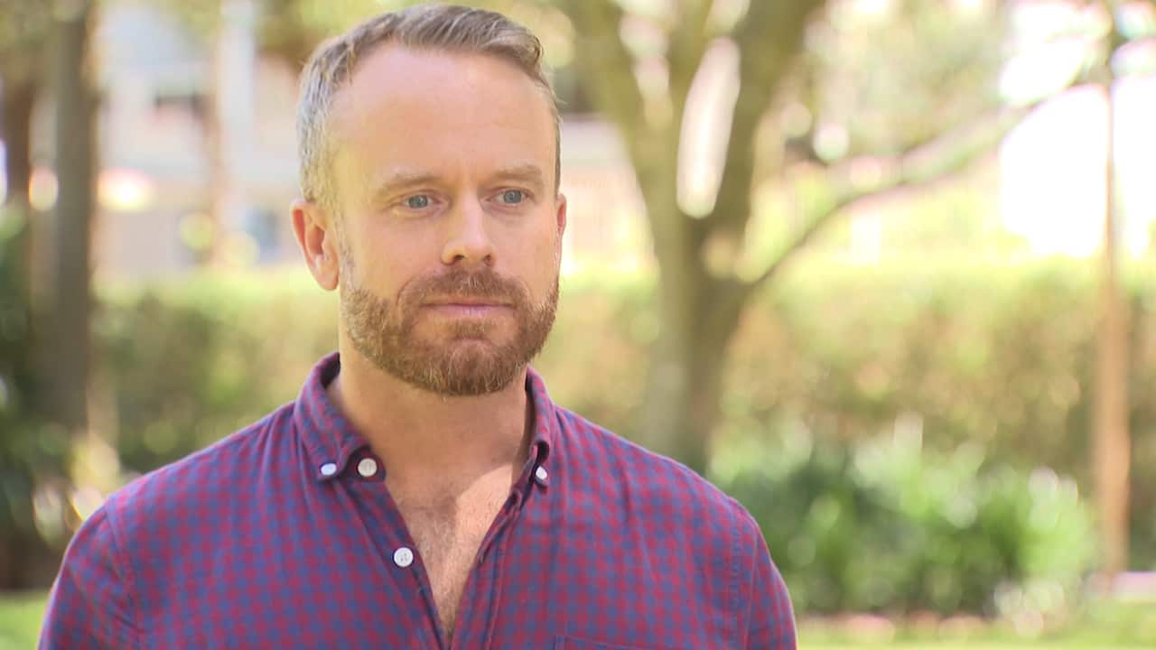 A man wearing a purple shirt standing outside