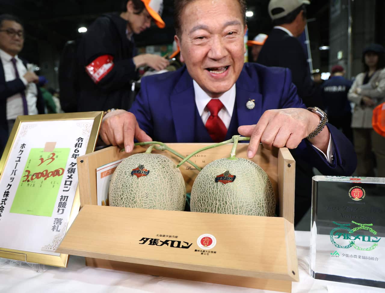 Japanese melons for auction in a wooden box with a man displaying them.