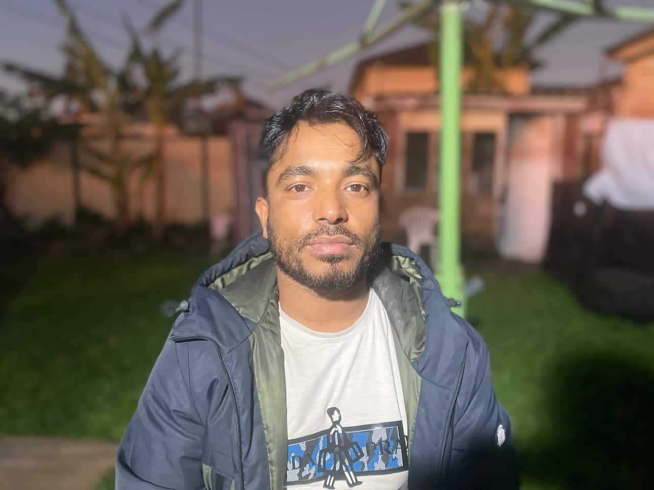 A man wearing a t-shirt and jacket and standing outside