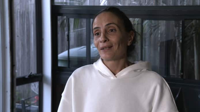 A middle-aged woman wearing a white hoodie 