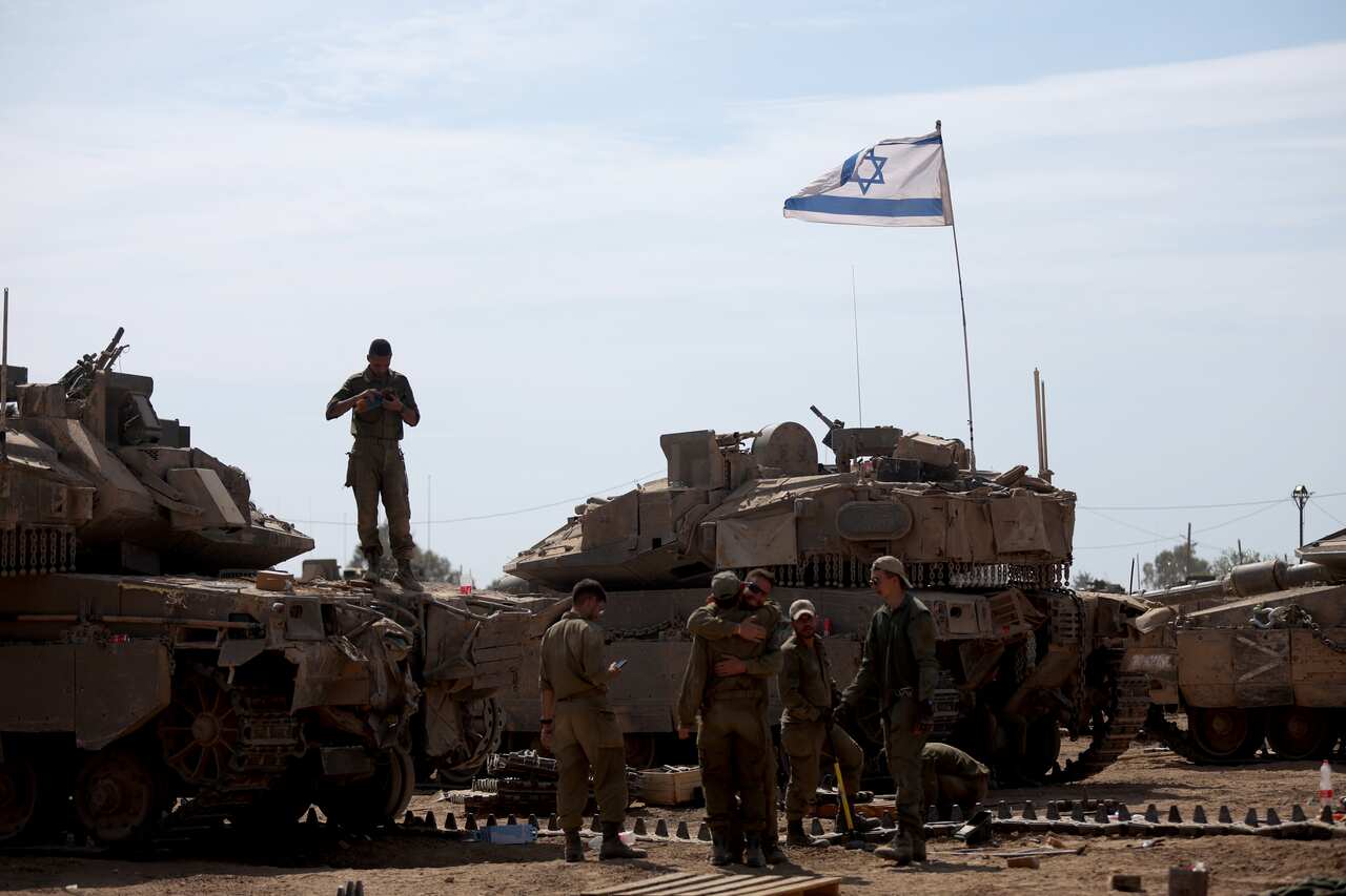 Israeli soldiers stand next to their tanks.