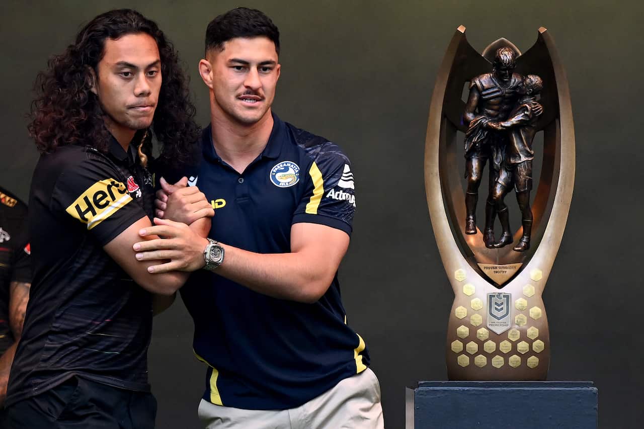 Two players shake hands in front of a trophy