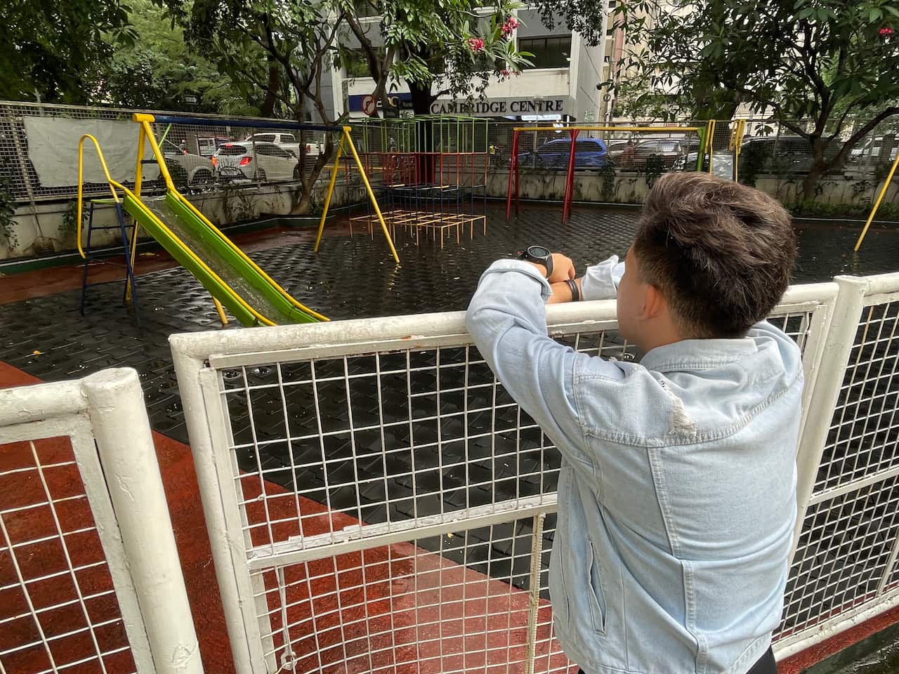 A young man, shot from behind, looking at a child's playground