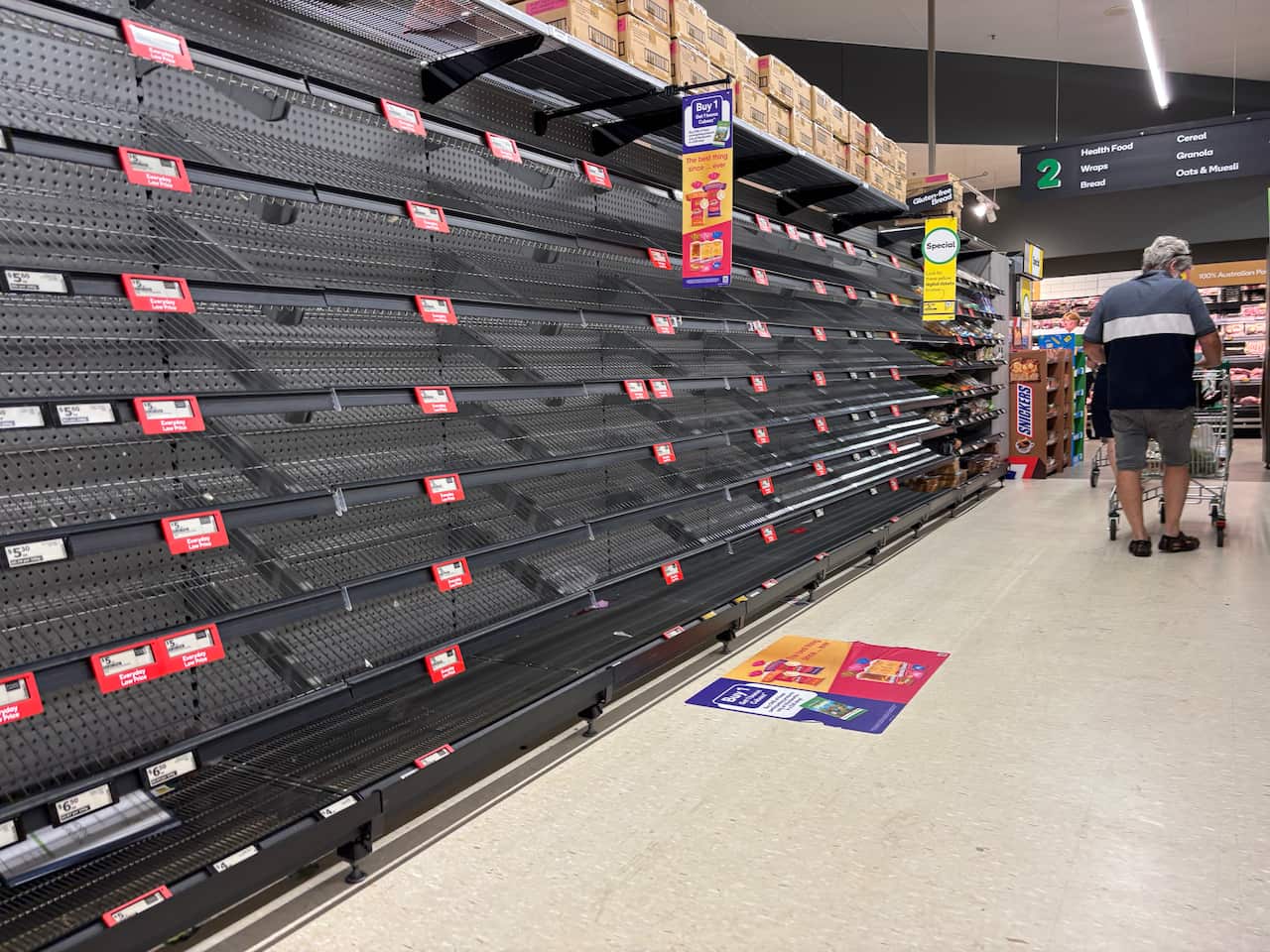 A man in a supermarket with empty shelves