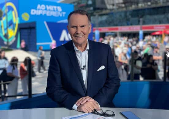 A smiling man wearing a navy suit