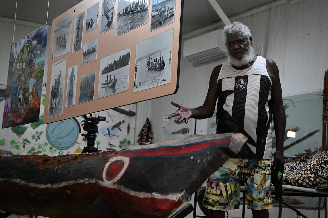 Bernard Tipiloura stands with a hand carved canoe inside