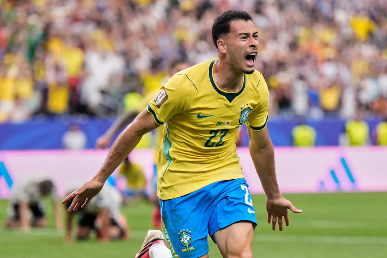 Gabriel Martinelli, a football player in his late 20s in a yellow jersey with the number 22 on it, celebrates a goal on a football pitch.
