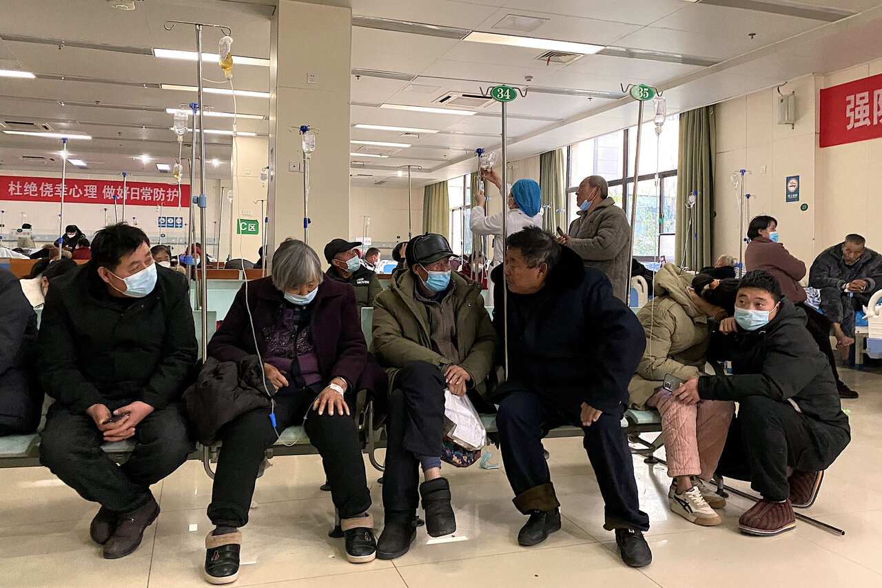 People sitting on benches inside a hospital.