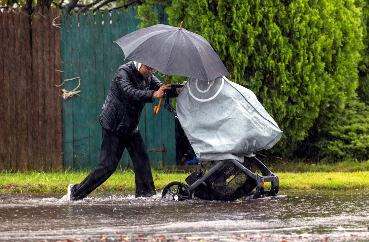 Pedestrian with a baby stroller walks through flooded Long Island street