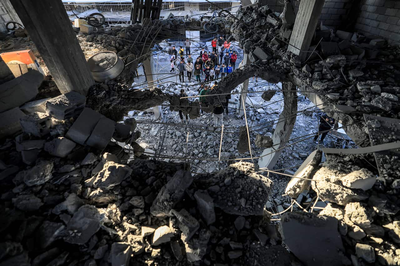 A crowd looks up at the rubble of a building hit by an Israeli airstrike