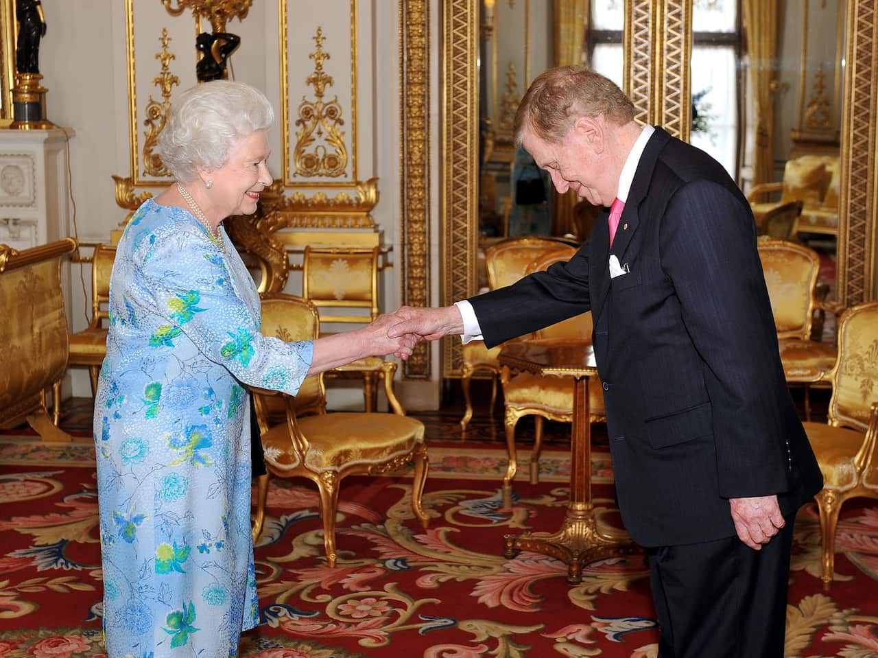 Michael Kirby shaking hands with Queen Elizabeth inside an ornate palace room.