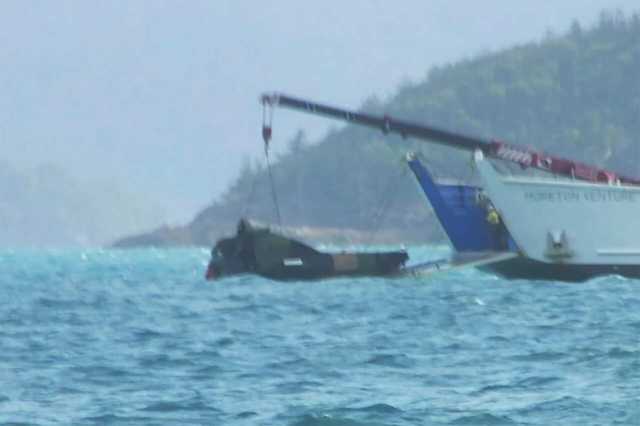 Grainy image of part of a helicopter being retrieved from the water.