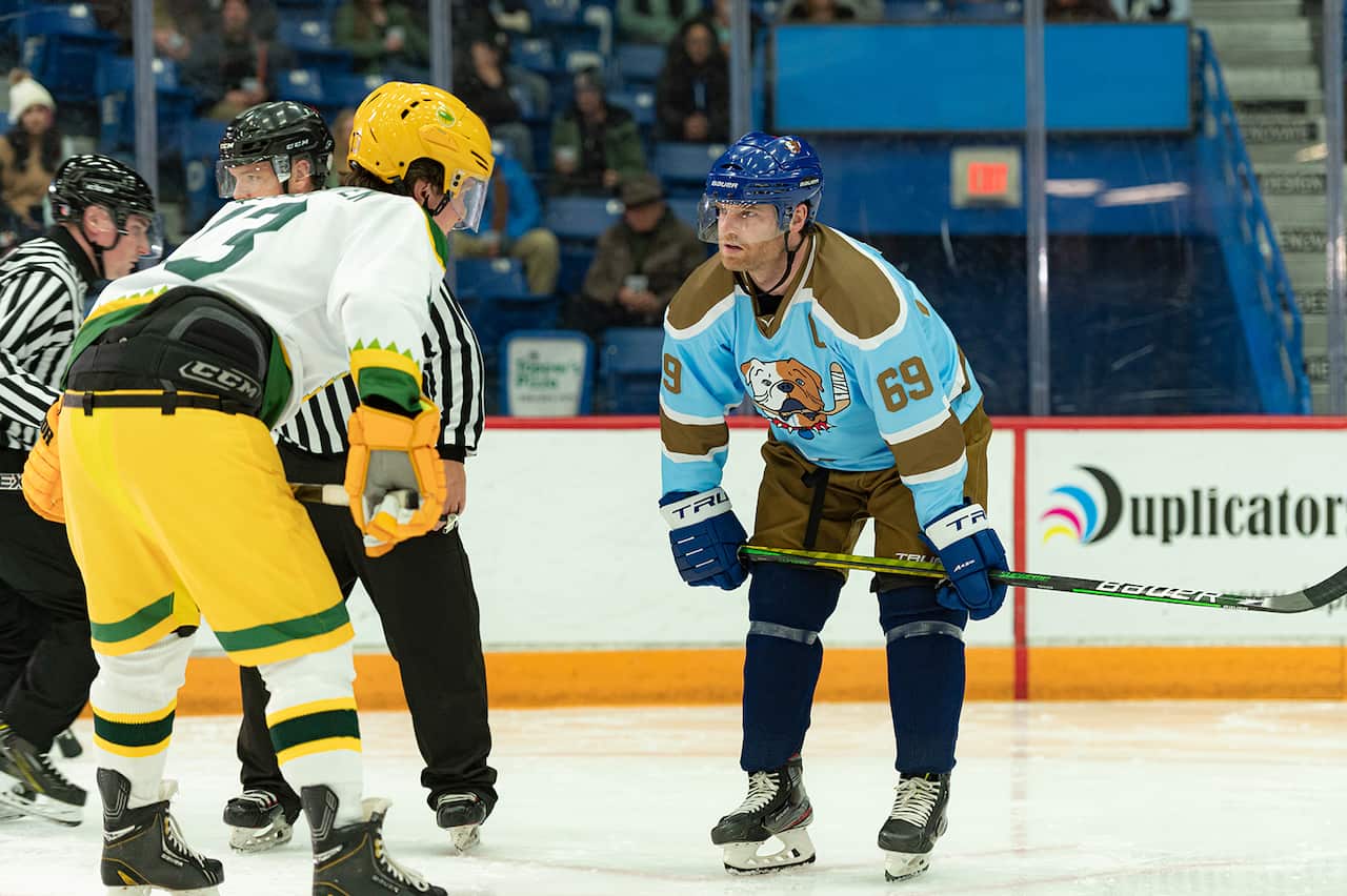 A hockey player in a blue uniform faces an opponent on the ice. 