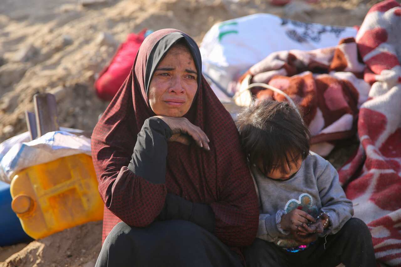 A woman and child sit on rubble